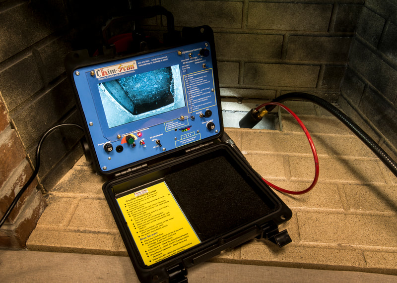 A Chim-Scan monitor is sitting in a firebox while the camera is inserted into the ash pit.