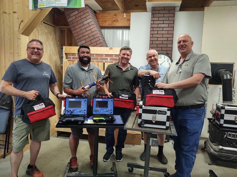 Five men are smiling as they hold Chim-Scan equipment after the Chim-Scan Factory Training.
